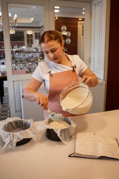 Foto gratuita pasticcere femminile che versa la pasta in uno stampo