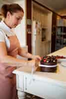 Foto gratuita pasticcere femminile con torta al cioccolato in pasticceria