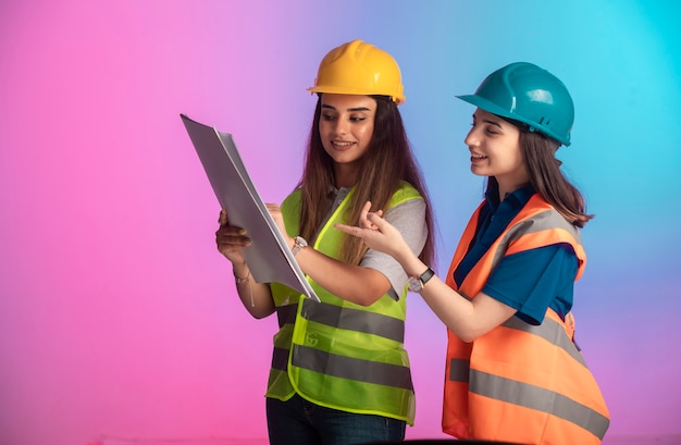 Free photo female construction engineers working together and discussing the project plan on colorful.