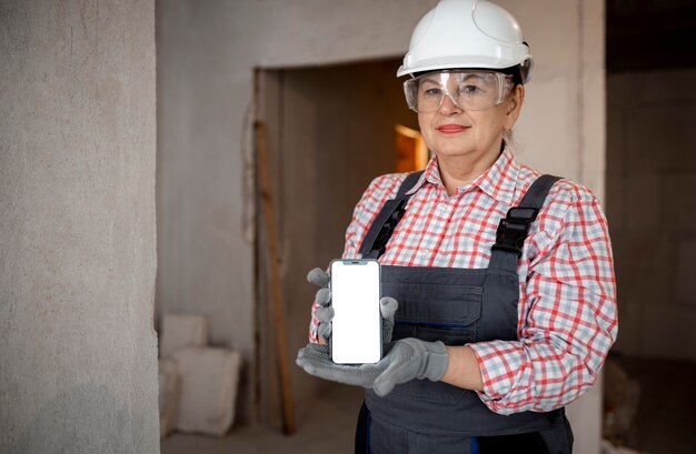 Female construction worker with helmet holding smartphone