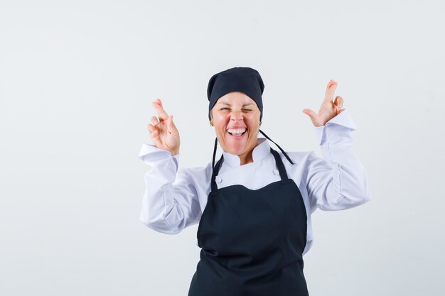 손가락을 유지하는 여성 요리사는 유니폼, 앞치마를 입고 행복하게 보입니다. 전면보기.