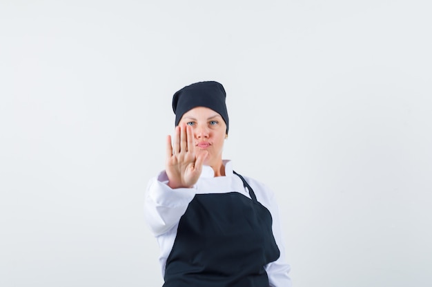 여성 요리사 유니폼, 앞치마에 중지 제스처를 보여주는 자신감을 찾고. 전면보기.