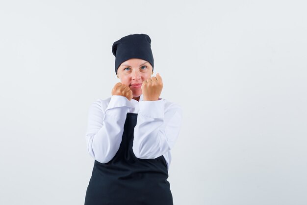유니폼, 앞치마와 자신감을 찾고 싸움 포즈에 서있는 여성 요리사. 전면보기.