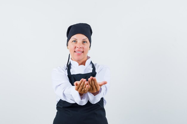 여성 요리사는 유니폼, 앞치마에 손을 뻗어 낙관적입니다. 전면보기.