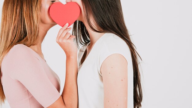 Female couple kissing behind heart