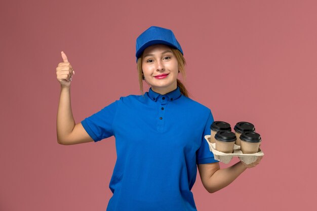 분홍색, 서비스 유니폼 배달 작업 노동자에 약간의 미소로 커피 갈색 배달 컵을 들고 파란색 제복을 입은 여성 택배