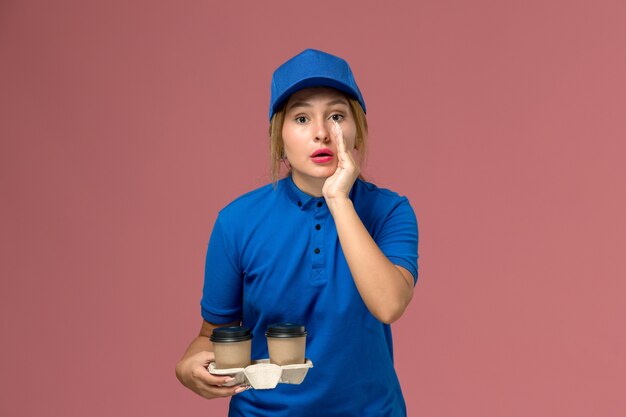 핑크, 서비스 유니폼 배달 작업에 속삭이는 커피 잔을 들고 파란색 유니폼 여성 택배