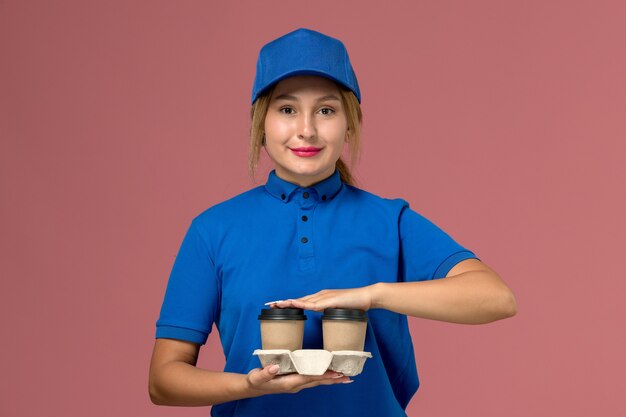분홍색, 서비스 균일 한 배달 작업에 웃 고 커피 배달 컵을 들고 파란색 제복을 입은 여성 택배