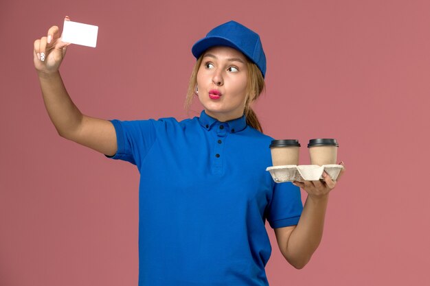 분홍색, 서비스 균일 한 배달 작업자 작업에 커피와 흰색 카드의 배달 컵을 들고 파란색 제복을 입은 여성 택배