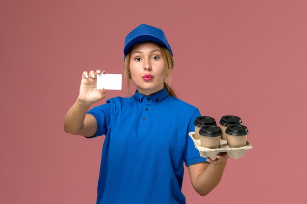 밝은 분홍색, 서비스 작업 유니폼 배달에 커피 갈색 배달 컵과 함께 흰색 카드를 들고 파란색 유니폼 여성 택배