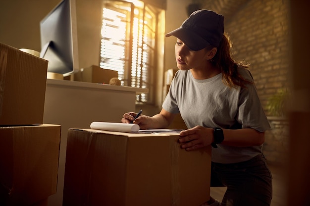 Female courier going through a list while preparing packages for delivery in the office