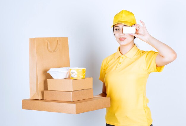 Female Courier holding packages on a white wall