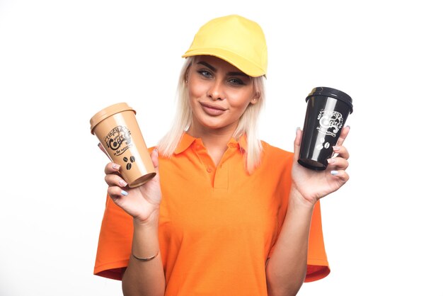 Female courier holding two cups of coffees on white background. High quality photo