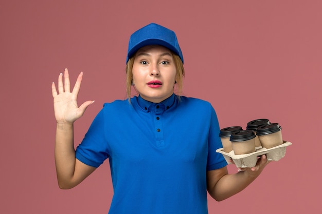 無料写真 ピンクのコーヒーの茶色の配達カップを保持している青い制服を着た女性の宅配便、サービスワーカーの制服配達