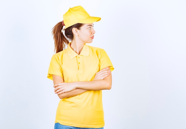 Бесплатное фото Женский курьер в желтой форме скрещивает руки и принимает профессиональные позы.