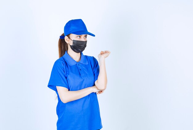 Female courier in mask and blue uniform thinking and planning.