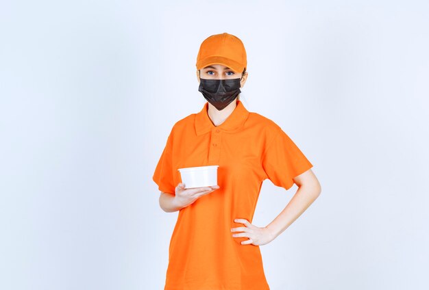 주황색 제복을 입은 여성 택배와 플라스틱 컵을 들고 있는 검은색 마스크