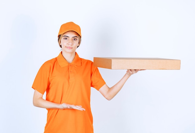 Женский курьер в оранжевой форме доставляет картонную коробку