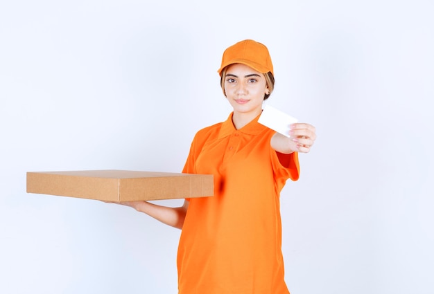 段ボール箱を保持し、名刺を提示するオレンジ色の制服を着た女性の宅配便