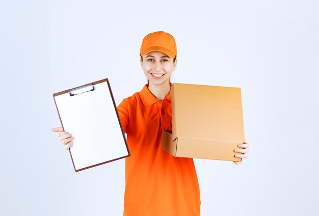 Female courier in orange uniform holding an open cardboard box and asking for a signature