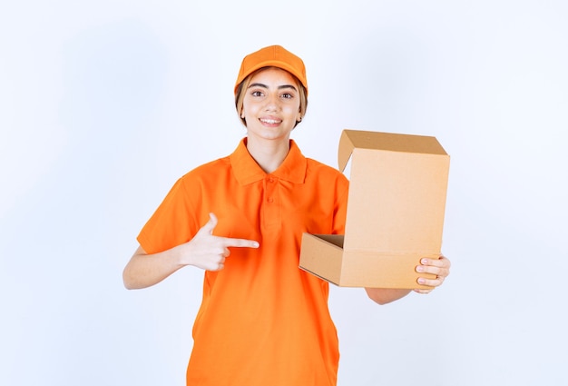 Female courier in orange uniform holding an open cardboard box