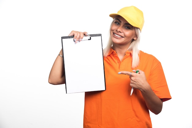Female courier pointing at empty notebook while holding pen on white background. High quality photo