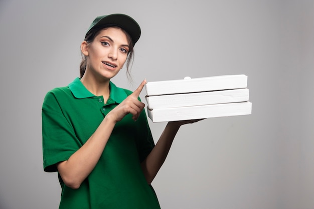 Женский курьер позирует с коробками для пиццы