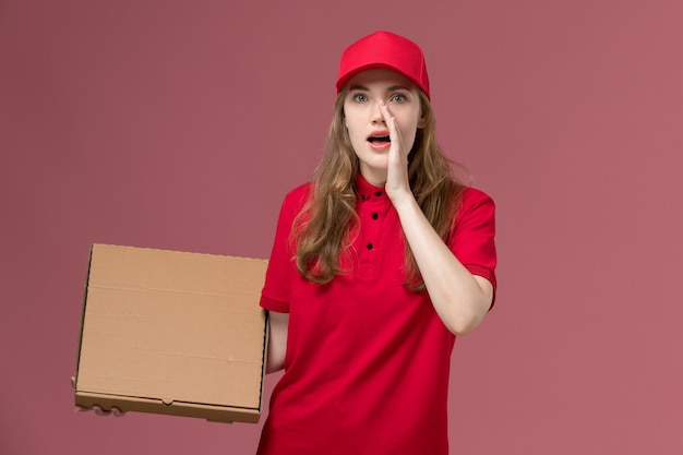 갈색 음식 배달 상자를 들고 분홍색, 균일 한 서비스 배달 작업자에게 속삭이는 빨간 제복을 입은 여성 택배