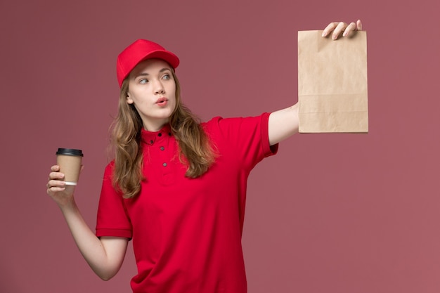 분홍색, 균일 한 서비스 배달 작업에 음식 패키지와 함께 커피 컵을 들고 빨간색 제복을 입은 여성 택배