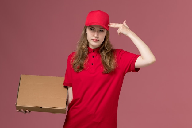 female courier in red uniform holding food delivery box thinking on pink, uniform service delivery job worker