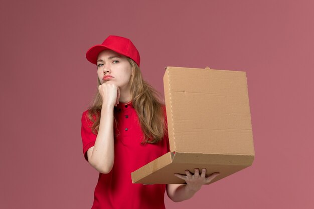 female courier in red uniform holding opening food box on pink, uniform service delivery job