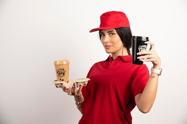 Female courier showing coffee cups on white background. High quality photo