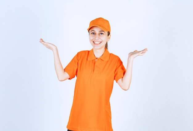 Foto gratuita corriere femminile che indossa l'uniforme arancione e il berretto rivolto su entrambi i lati.
