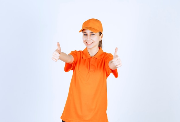 Foto gratuita corriere femminile che indossa un'uniforme arancione e un berretto che mostra il pollice in su