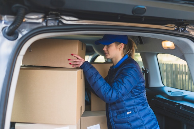 Free photo female courier with boxes in car