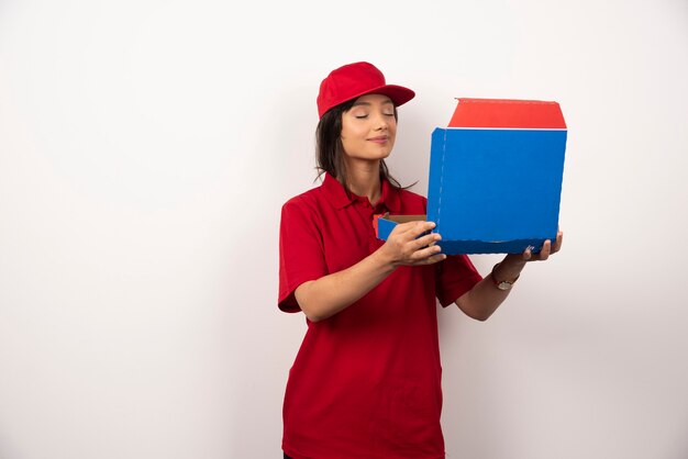 Female courier with closed eyes holding a box of pizza