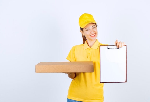 黄色い制服を着た女性の宅配便業者が小包を配達し、顧客に署名を求めました。
