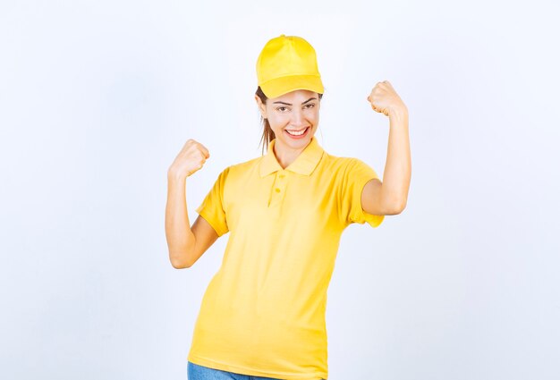 Female courier in yellow uniform demonstrating her arm muscles. 