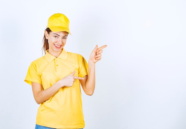 Female courier in yellow uniform pointing at somewhere. 