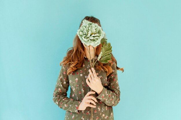 Female covering face with fresh flower