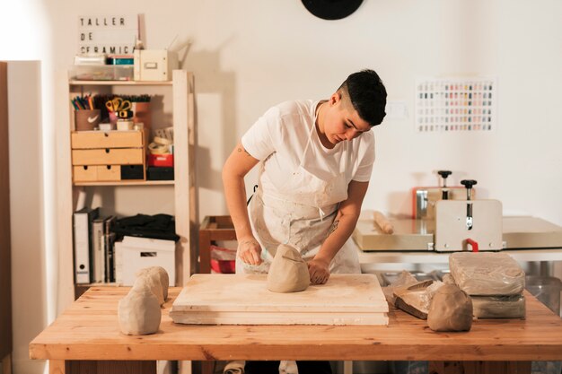 Female craftswoman cutting a kneaded clay with thread on the table