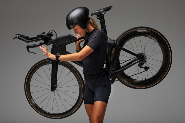 Female cyclist wearing helmet and posing with bicycle