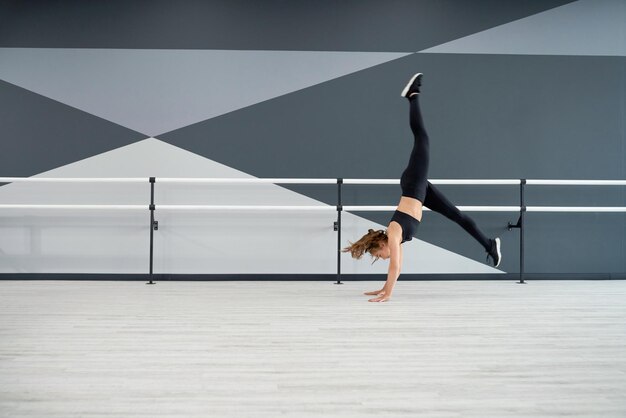 Female dancer practicing wheel jump in dance hall