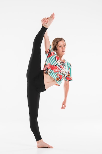 Female dancer stretching her leg up in front of white backdrop