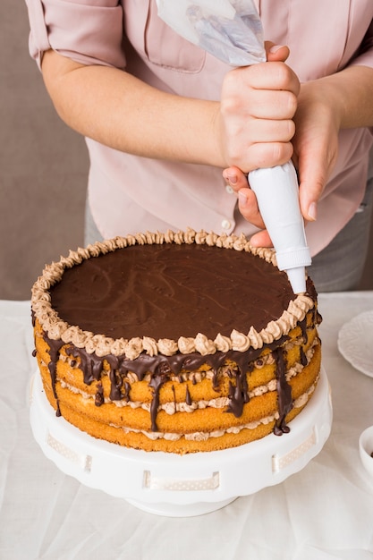 Female decorating delicious cake close up