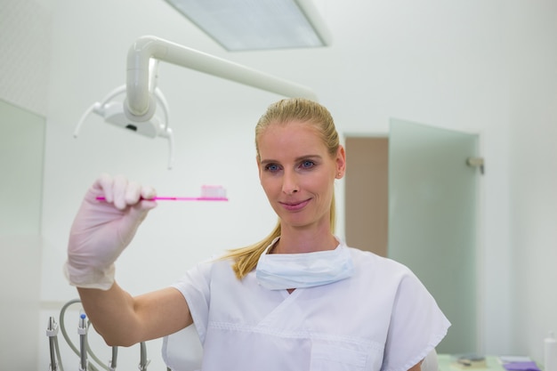 Женский стоматолог держит зубную щетку