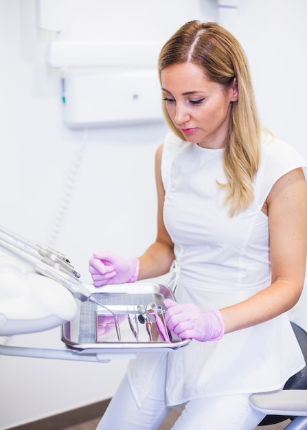 Female dentist looking at dental instruments on tray