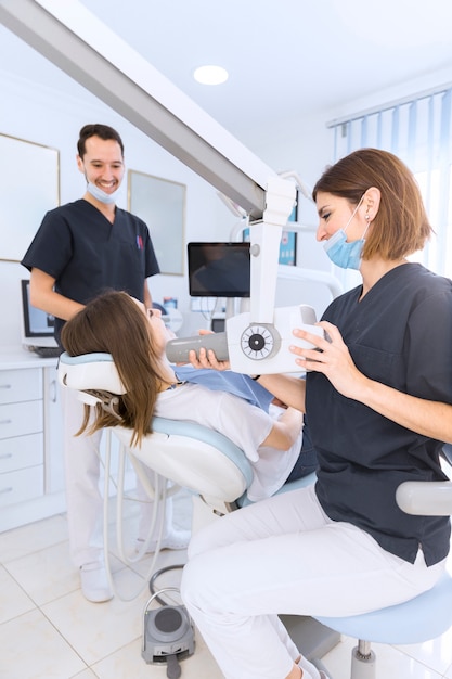엑스레이 기계로 환자의 치아를 스캔하는 여성 치과 의사