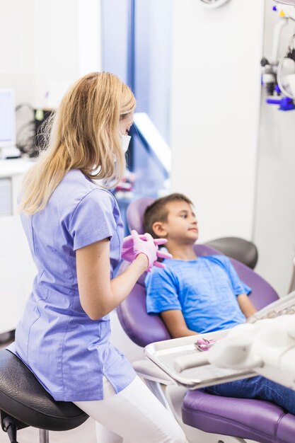 Female dentist sitting near boy in clinic