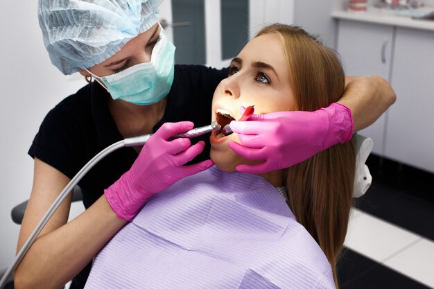 Женский дантист, лечащий ее пациентские зубы